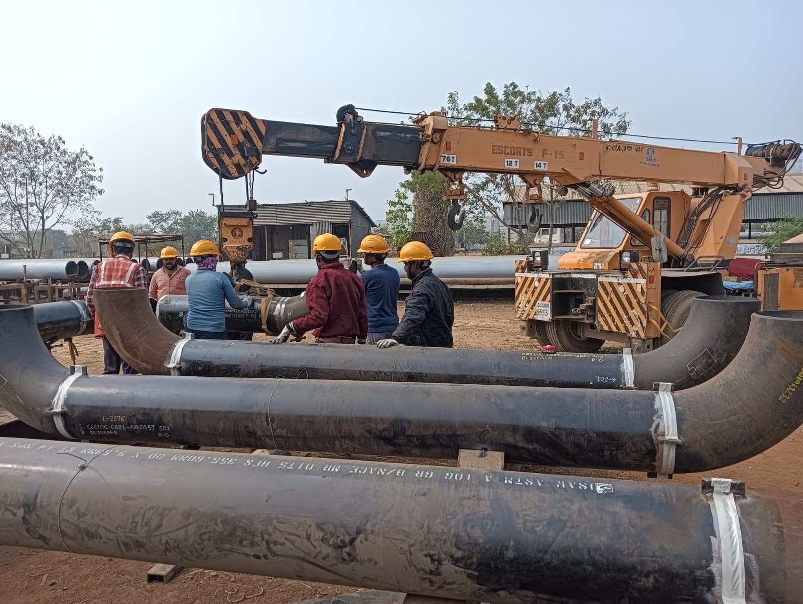 Carbon-steel pipe spools being rigged with a mobile crane by the site crew
