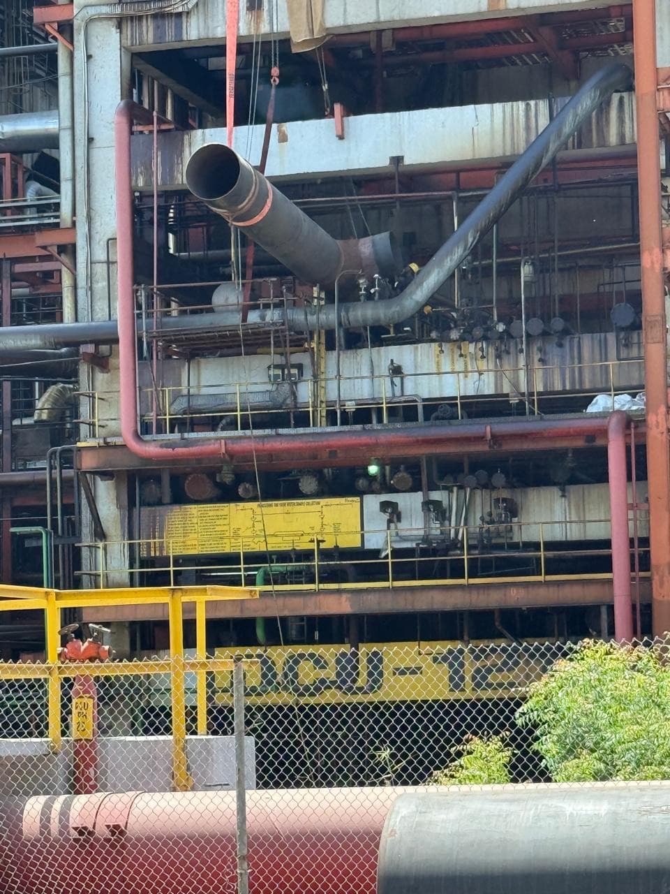 Large-bore process piping running through a tall multi-level plant structure at an operating industrial site