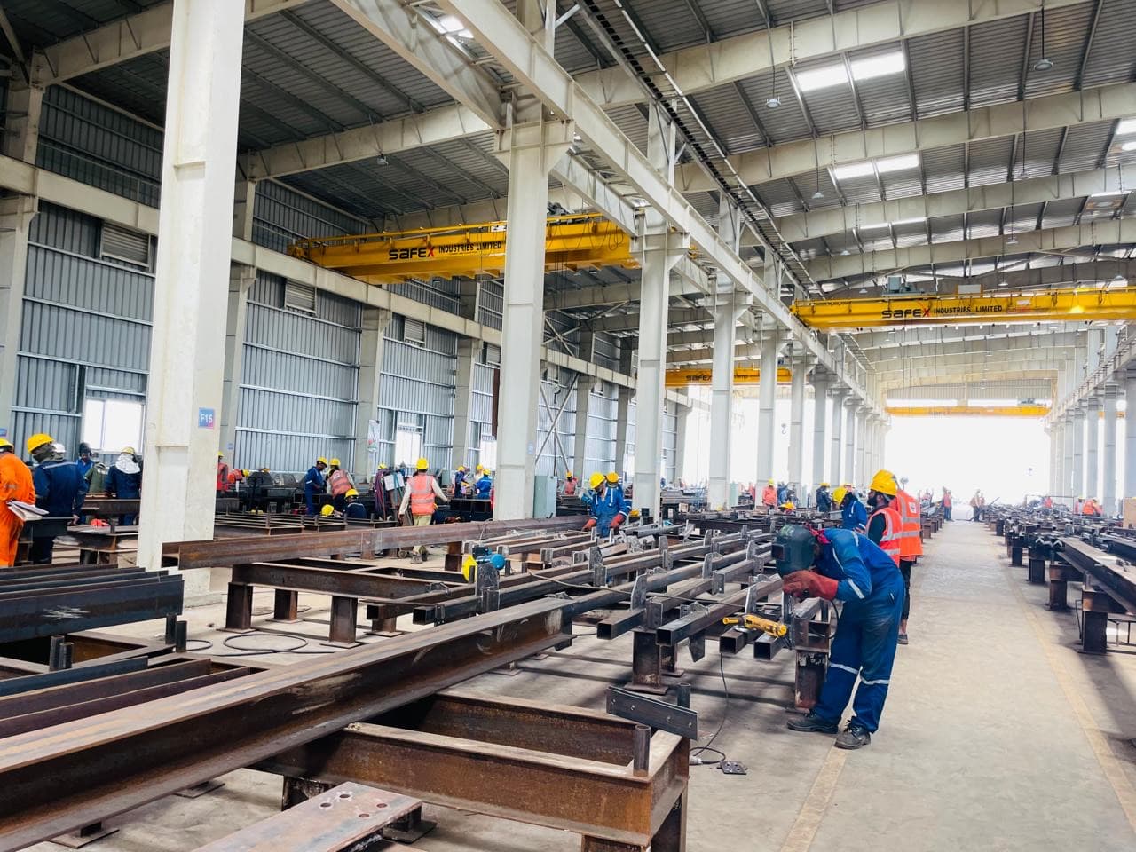 Interior of Nectar Engineering's fabrication workshop — steel members being fabricated by the crew beneath overhead travelling cranes